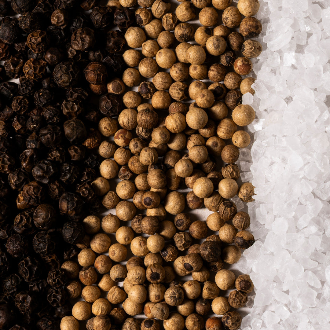 Three types of peppercorns arranged in a row on a white background.