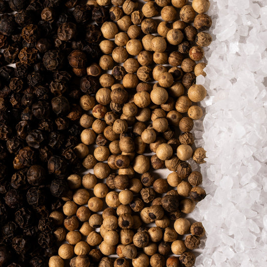 Three types of peppercorns arranged in a row on a white background.