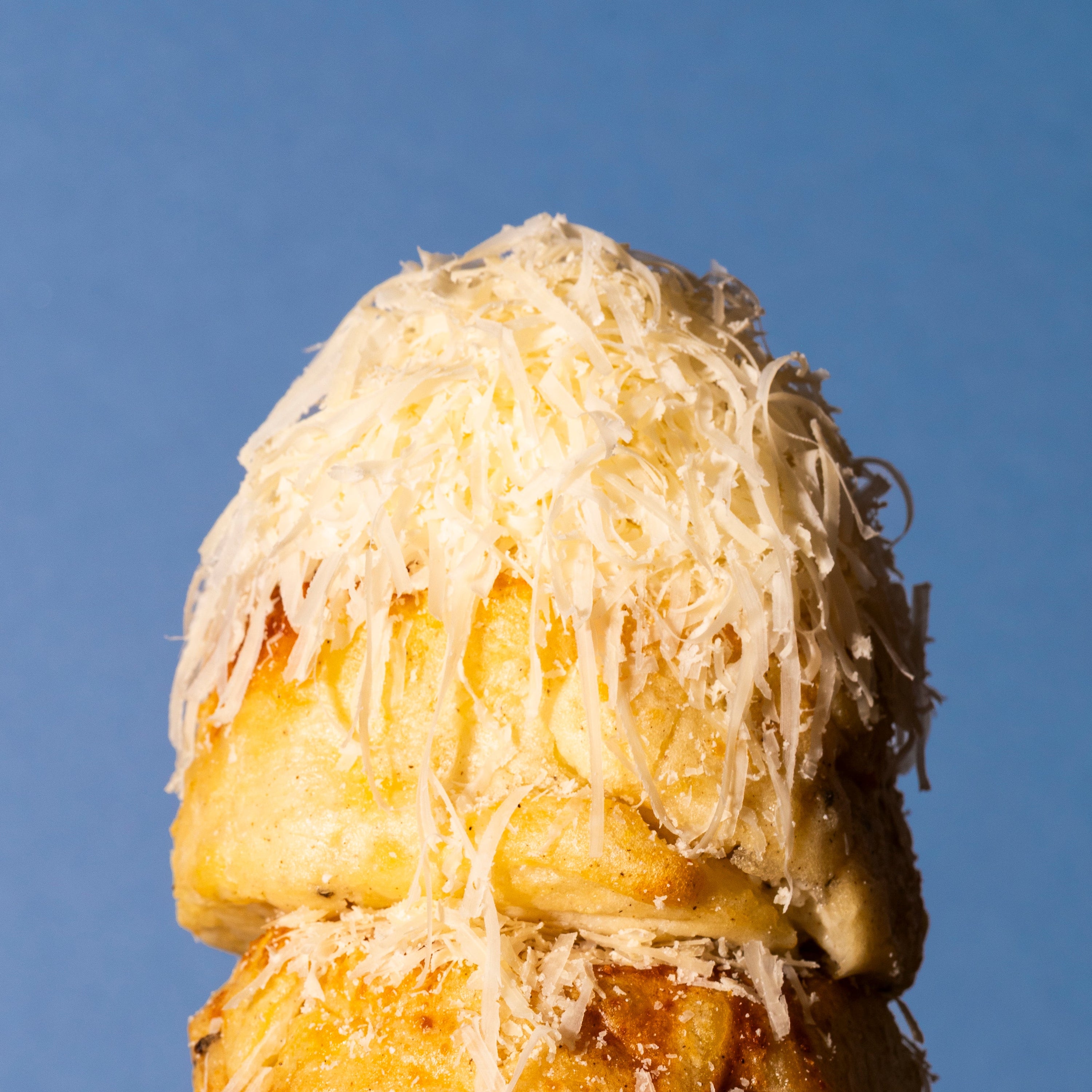 Stack of cheesy gratins on a plate against a blue background