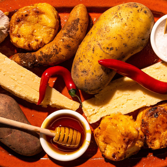 Wooden tray with various ingredients including potatoes, cheese, spices and gratins on a white background