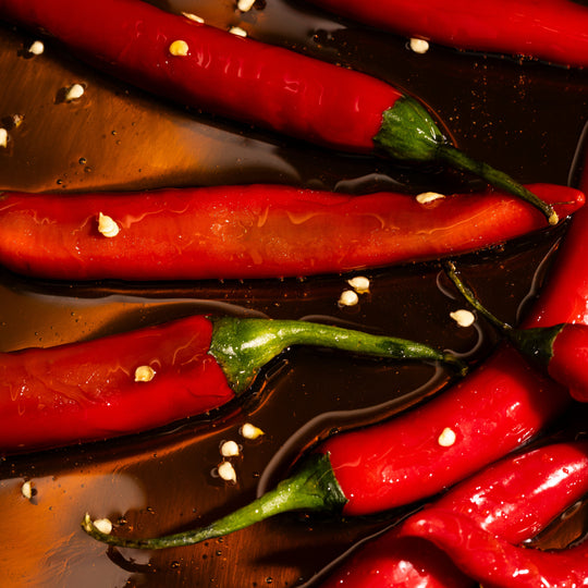 Red chili peppers on a dark surface with oil