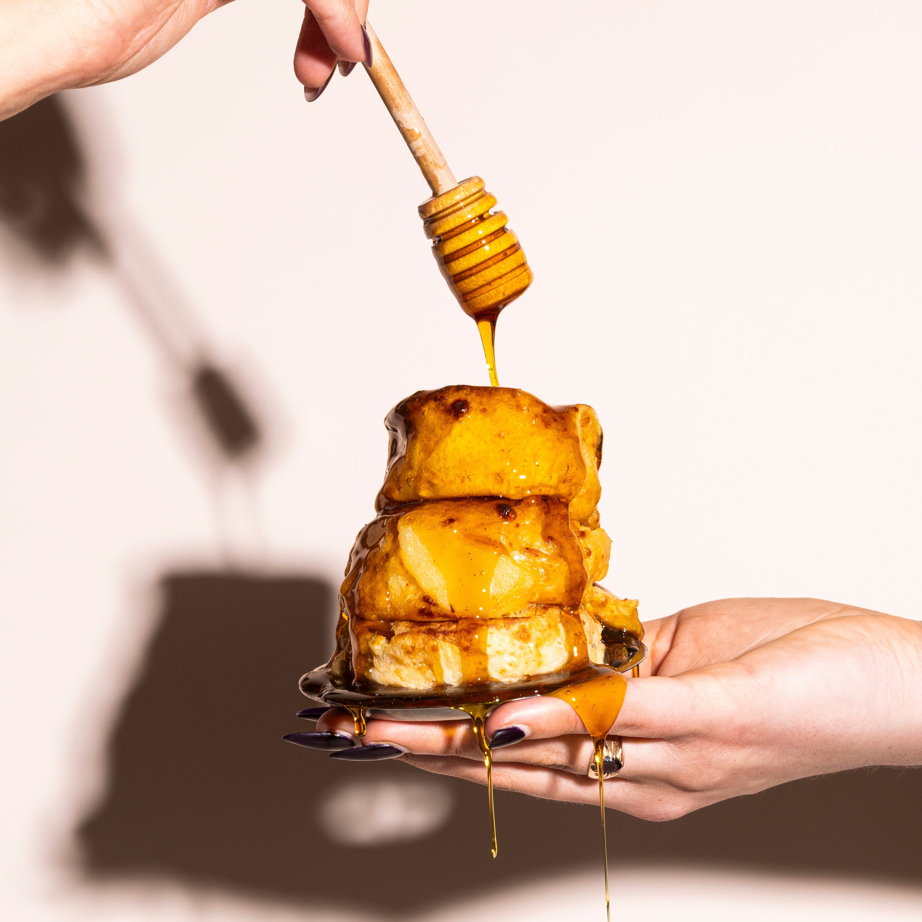 Honey being drizzled onto stack of hot honey and mozzarella flavoured gratins